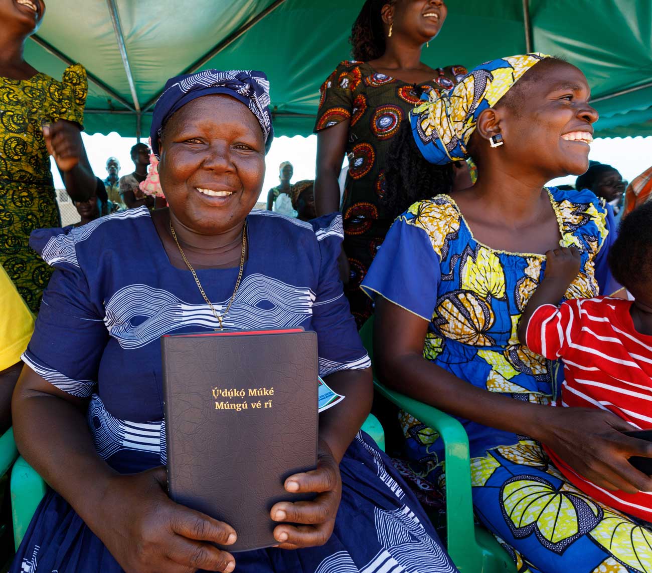 Smiling woman holds up new Bible at Scripture celebration